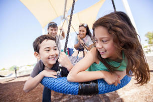 Happy family portrait on a playground swing